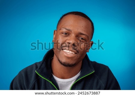 Cheerful young man with a bright smile against blue background