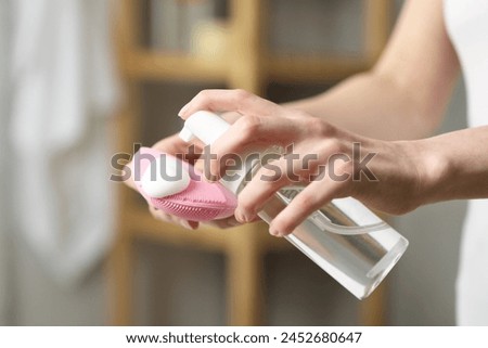 Washing face. Woman applying cleansing foam onto brush in bathroom, closeup