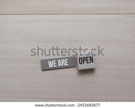 sticky note and square magnet with the word We Are Open on wooden background. shop open concept