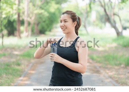 Asian woman drinking water after jogging. Health care concept. Drinking enough water per day. Royalty-Free Stock Photo #2452687081