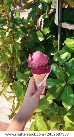 Close isolated view of ice cream cone in hand of women standing outdoors Royalty-Free Stock Photo #2452687339