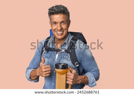 Hispanic trekker with backpack and flashlight smiling and raising thumb up
