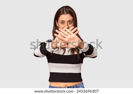 Elegant middle-aged Caucasian woman in studio setting doing a denial gesture