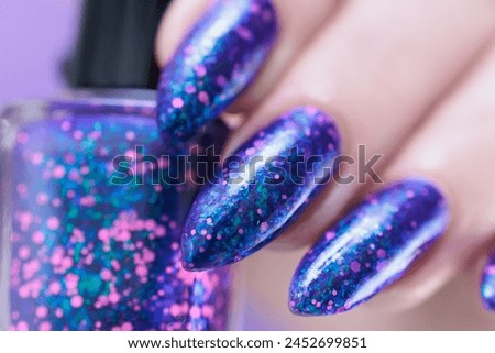 Female hand with long nails and a blue and lilac color nail polish