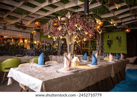 The image shows a beautifully decorated restaurant interior with a floral-adorned ceiling and elegant table settings.