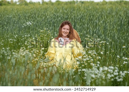 Happy portrait of a young beautiful red hair girl in a summer field