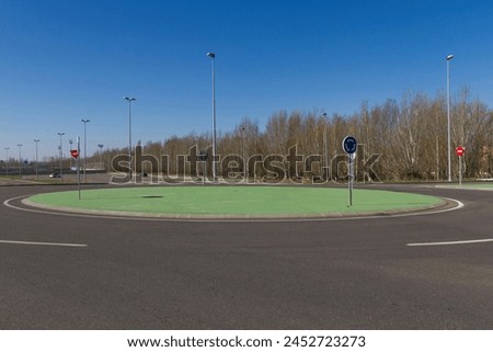 Roundabout  of new construction, designed in cement painted green simulating grass. On the outskirts of an urban space, with vertical traffic signaling