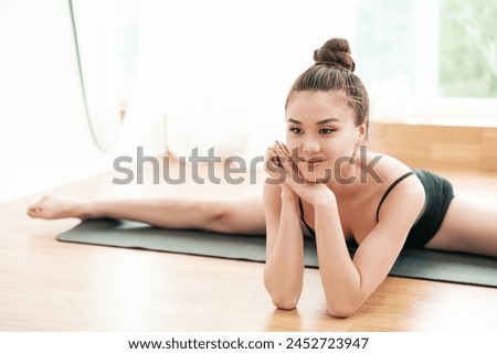 Beautiful woman of Asian appearance sits in a twine. Great background for a choreography, fitness or gymnastics commercial presentation. 