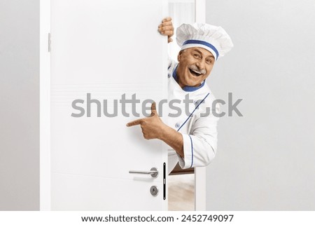 Chef in a uniform opening a door and pointing 