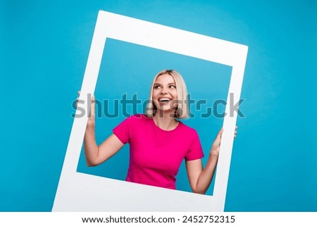 Photo portrait of lovely young lady hold photo frame look empty space dressed stylish pink clothes isolated on blue color background