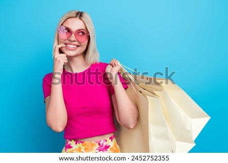 Photo portrait of attractive young woman hold shopping bags look empty space dressed stylish pink clothes isolated on blue color background