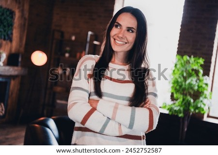 Photo of lovely young woman folded hands look empty space wear striped outfit interior home living room in brown warm color