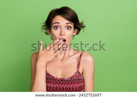 Photo of anxious embarrassed woman wear stylish clothes hand cover mouth omg isolated on green color background