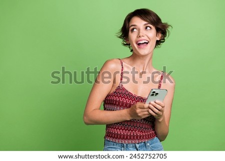 Photo of cheerful adorable girl user wear trendy clothes hold apple iphone look blank space poster isolated on green color background