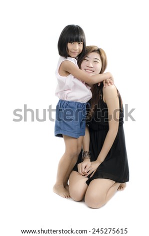 Two sisters embracing each other looking at the camera on white background.