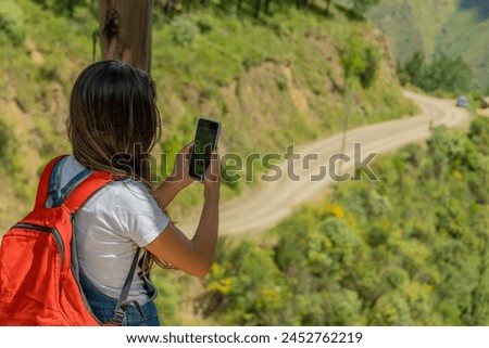 A young traveler taking a picture of the landscape with her phone
