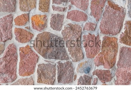 It's close up view of colorful wall. Its photo of the multicolor stonewall. It is photo of multicolored srone wall. its view of red sidewalk. It's view of mosaic color stones