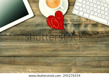 Red love heart, tablet pc, keyboard and coffee on wooden table. Valentines Day workplace. Retro style toned picture