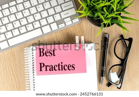 BEST PRACTICES text pink sticky on a notebook with keyboard, pen and glasses . 