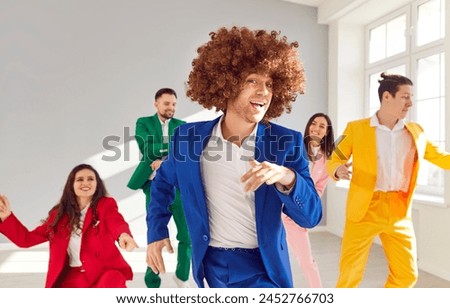 Happy dancing friends, group of bright people in vibrant vivid formal suit in cool dance, office party fun. Young cute disco team in color suit set wear, express enjoyment, colorful mood, event  Royalty-Free Stock Photo #2452766703