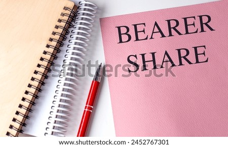 BEARER SHARE text on a pink paper with notebooks .  Royalty-Free Stock Photo #2452767301