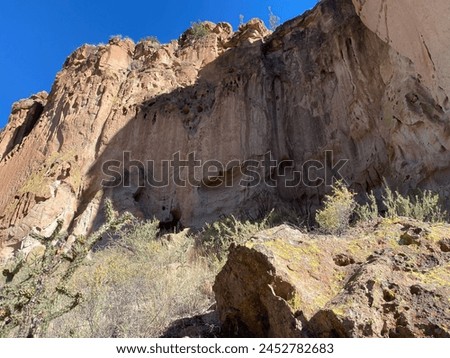 Bandelier National Monument preserves Ancestral Puebloan homes in New Mexico. Main Pueblo Loop Trail Long House with numerous petroglyphs (carved rock drawings) in cliff face. Macaw petroglyph. Royalty-Free Stock Photo #2452782683
