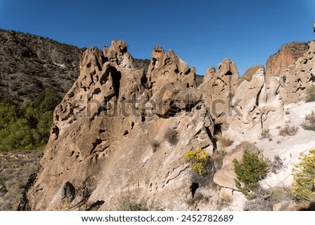 Bandelier National Monument in New Mexico. Hot ash from volcano at Valles Caldera cooled and welded into a rock called tuff. Pajarito Plateau and Frijoles Canyon show Volcanic Geology.  Royalty-Free Stock Photo #2452782689