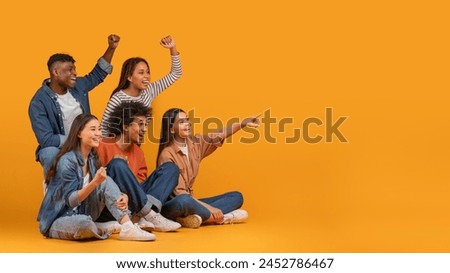 Multiethnic friends excitedly cheering and pointing to the side, exemplifying celebration and happiness in a diverse group, isolated on a yellow background, copy space Royalty-Free Stock Photo #2452786467