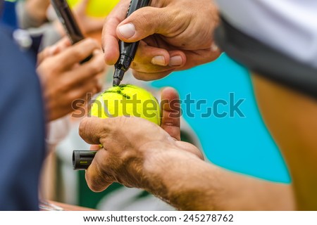 Tennis player signs autograph on a tennis ball after win, closeup photo showing tennis ball and hands of a man making signature, Australian open, US open. Royalty-Free Stock Photo #245278762