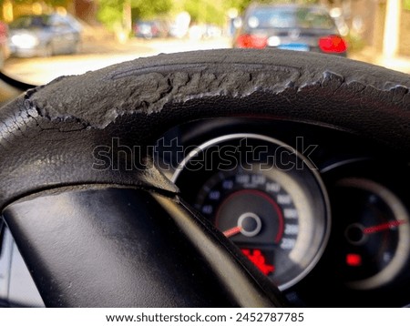cracks and damaged rubber of the car steering wheel due to long exposure to the sunlight, substandard materials in the manufacture of automotive parts, Close-up, selective focus of a damaged wheel Royalty-Free Stock Photo #2452787785
