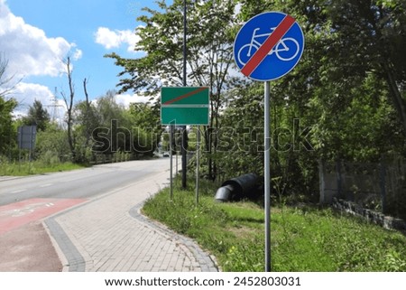 End of the bike path road sign. Bicycle road end information sign against the background of signs of the boundaries of a city or locality.