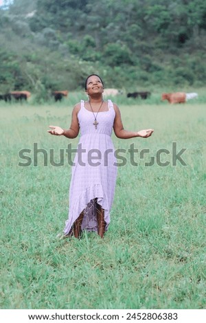 Black woman, from the Northeast representing the Northeast of Brazil. she is in a natural environment, contemplating nature and giving thanks. Royalty-Free Stock Photo #2452806383