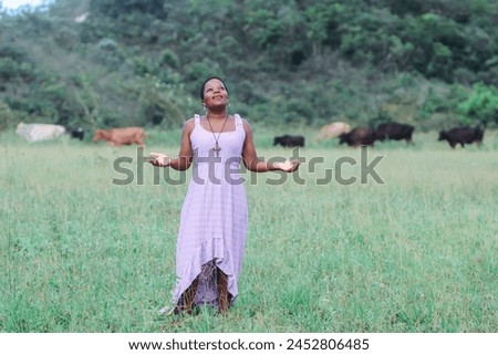 Black woman, from the Northeast representing the Northeast of Brazil. she is in a natural environment, contemplating nature and giving thanks. Royalty-Free Stock Photo #2452806485
