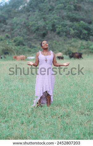Black woman, from the Northeast representing the Northeast of Brazil. she is in a natural environment, contemplating nature and giving thanks. Royalty-Free Stock Photo #2452807203