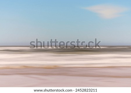 An abstract view of ocean waves creates a blurred horizon with a soft blue sky.