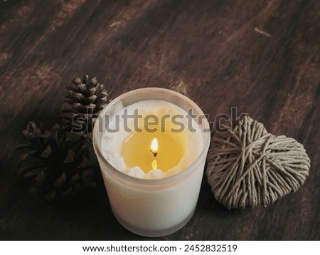 Scented candles with yarn hearts and pine cones on a vintage old wooden background for relaxation.