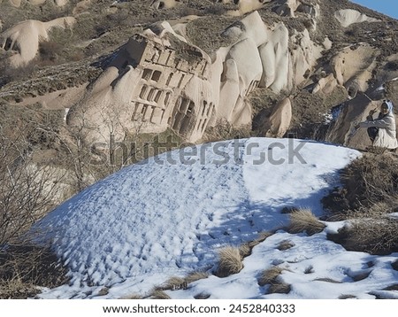 
a girl poses two toes in the snow on the ground of a rock cave background