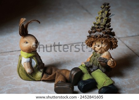 image of two cute cartoon show pieces - one with a big hat and nut in his hand in green dress and large boot and another easter bunny with long ear in green and white dress, portrait, folklore