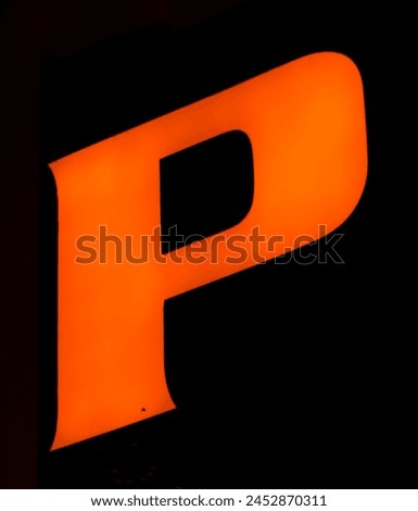 Fluorescent orange 'P' letter glows vibrantly against a shadowy backdrop, encapsulating power and presence Royalty-Free Stock Photo #2452870311
