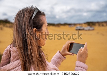 Female photographer taking pictures of sand and rocks in Pinnacles Desert.