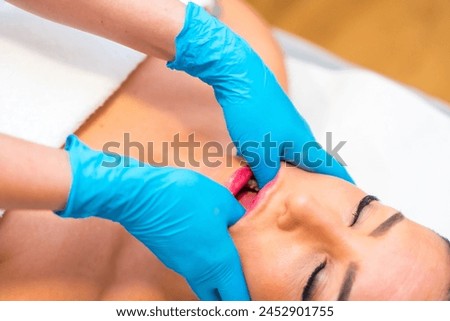 Close-up photo of a caucasian beauty adult woman receiving jaw massage to treat bruxism in a clinic