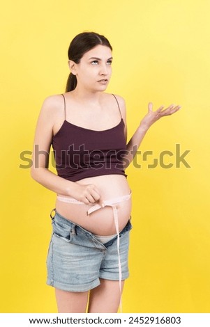 pregnant woman using tape measure to check baby development and the growth of belly. Inch measurement.