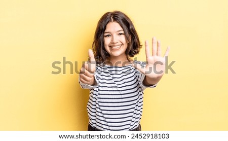 young pretty girl smiling and looking friendly, showing number six or sixth with hand forward, counting down Royalty-Free Stock Photo #2452918103