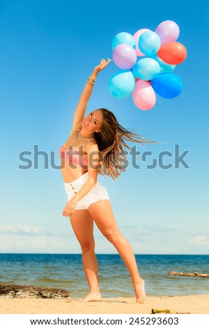 Summer holidays, celebration and lifestyle concept - attractive athletic woman teen girl with colorful balloons outside on beach seashore background