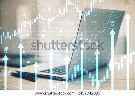 Close up of laptop computer and supplies at desk with growing blue vertical arrows and candlestick forex chart on blurry index grid background. Economic growth and increase concept. Double exposure