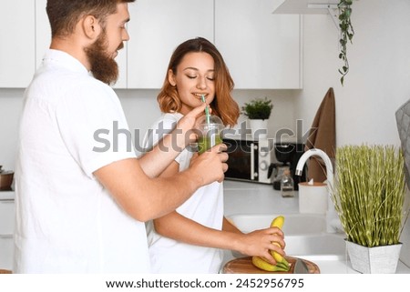 Happy couple in love with smoothie and bananas in kitchen