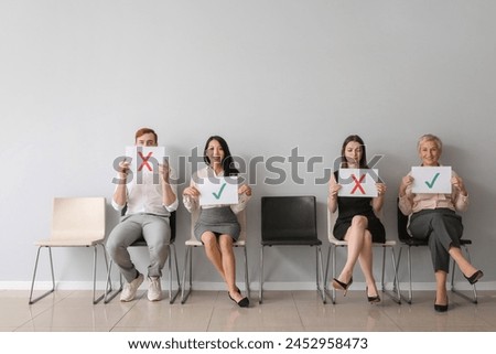 Applicants holding paper sheets with different marks near light wall