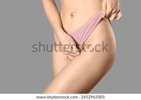 Young woman in panties on grey background