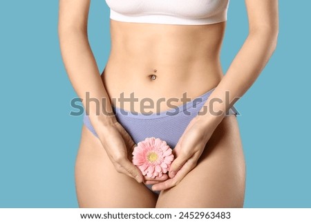 Young woman in panties with beautiful pink flower on blue background