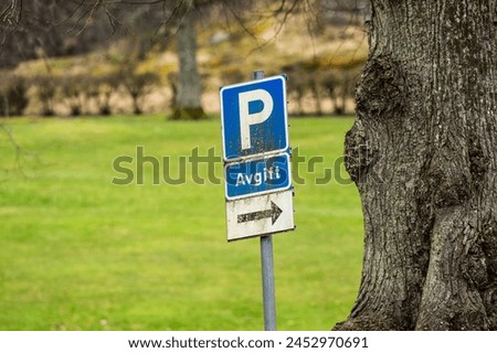 Old and weathered parking sign by a tree